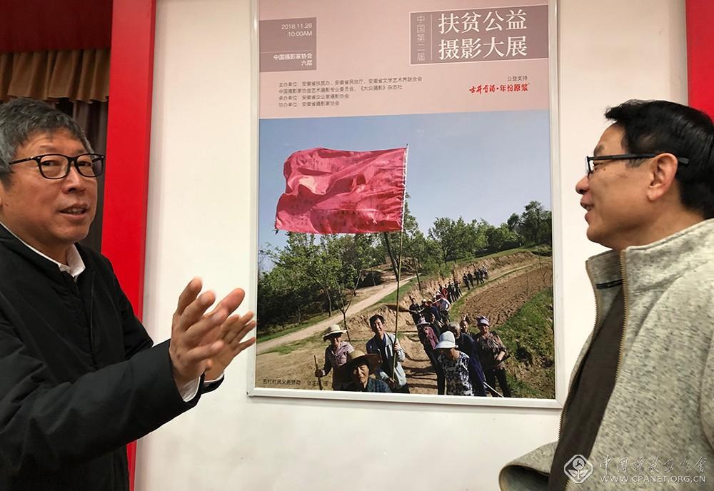 第一书记张国田(左)在招贴前讲述扶贫故事.jpeg 第一书记张国田(左)在招贴前讲述扶贫故事.jpeg