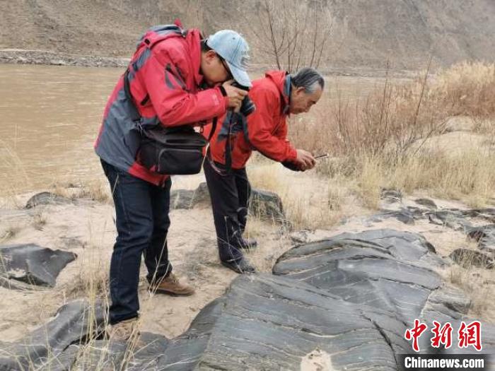 考古队正在拍摄新发现的人面像岩画（周兴华 摄）